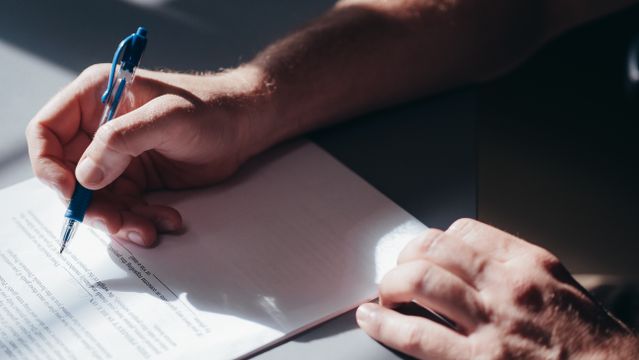 person looking over a document with a pen